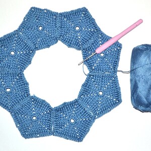 The process of joining crocheted pentagon motifs into the top part of a woman's hat.