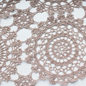 Beige crochet scarf with intricate as-you-go round motifs, photographed hanging in full view on a white background.