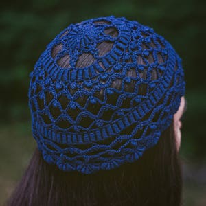 May include: A blue crocheted hat with a delicate pattern. The hat is made of yarn and has a soft, comfortable texture.