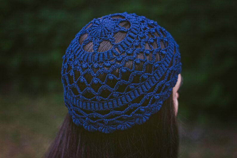 May include: A blue crocheted hat with a delicate pattern. The hat is made of yarn and has a soft, comfortable texture.