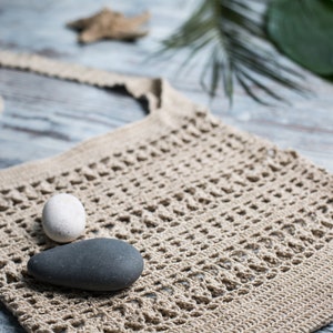 May include: A beige crocheted tote bag with two smooth stones inside. One stone is white and the other is gray.