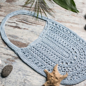 Soft blue handmade bag with one strap, flat lay with stones and starfish – feminine and minimal beach accessory