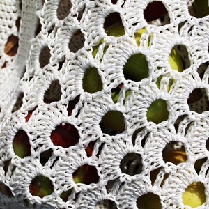 May include: White crocheted bag with a variety of apples inside. The apples are red, green, and yellow.