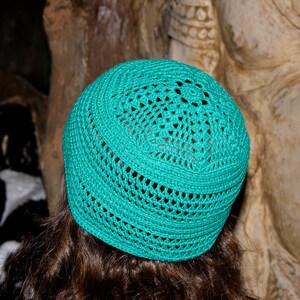 May include: A teal crocheted hat with a circular design. The hat is made of a soft, lightweight material and has a comfortable fit.
