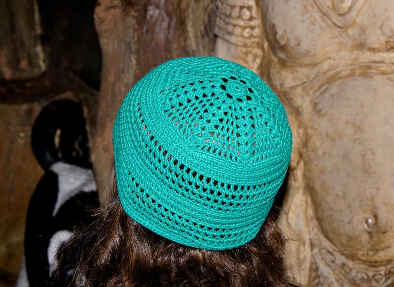 May include: A teal crocheted hat with a circular design. The hat is made of a soft, lightweight material and has a comfortable fit.