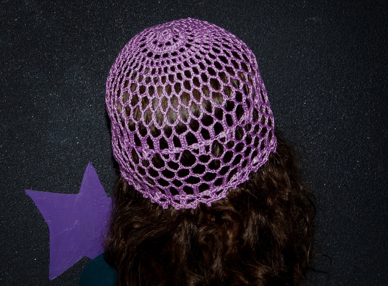 May include: A purple crochet hat with a delicate openwork design. The hat is made of soft yarn and has a comfortable fit.