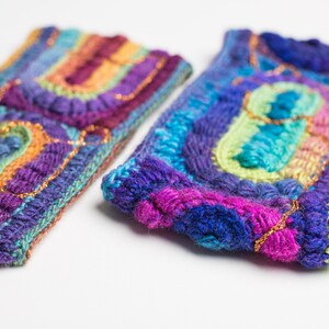 May include: Two colorful crocheted headbands with a rainbow pattern and gold accents. The headbands are made with a variety of different colored yarns.