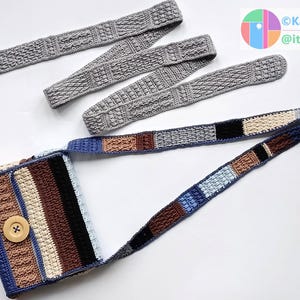 Könnte beinhalten: Gehäkelte Umhängetasche mit langem Riemen, Knopfverschluss und Patchwork-Design in Blau-, Braun-, Schwarz- und Cremetönen. Drei passende graue Häkelstirnbänder sind ebenfalls zu sehen. Die Tasche und Stirnbänder liegen auf weißem Grund.