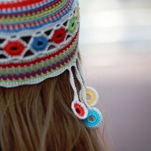May include: A colorful crocheted hat with a white crocheted tassel and colorful crocheted circles hanging from the tassel.