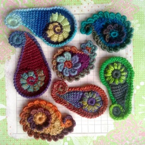 May include: Seven crocheted paisley shapes in various colours, including blue, red, purple, green, and brown. Each shape has a unique floral design in the centre.