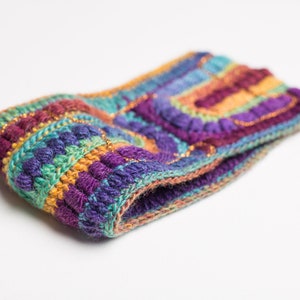May include: A colorful crocheted headband with a multi-colored striped pattern and gold accents.