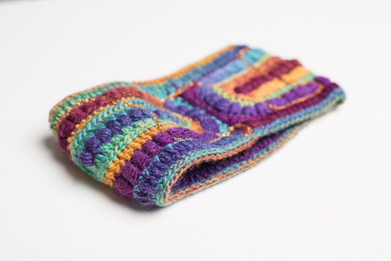 May include: A colorful crocheted headband with a multi-colored striped pattern and gold accents.