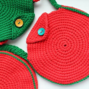 May include: Three crocheted watermelon-shaped bags with green and red yarn. The bags have a flap with a button closure.