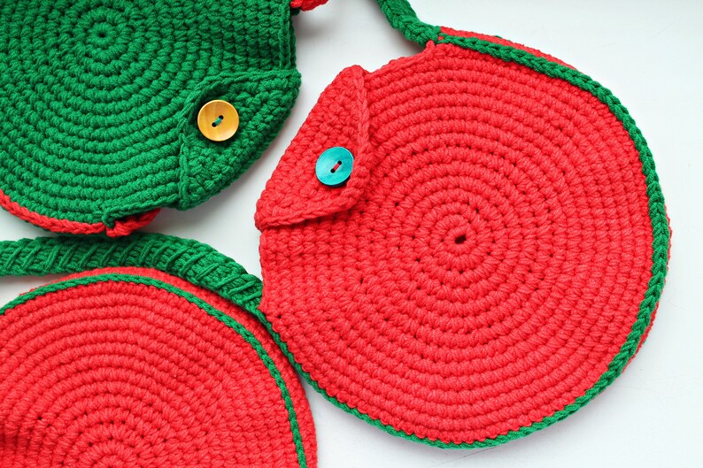 May include: Three crocheted watermelon-shaped bags with green and red yarn. The bags have a flap with a button closure.