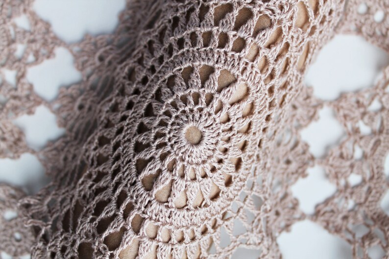 Close-up of large round crochet motif in beige linen yarn, showing delicate lace pattern and intricate stitch work.