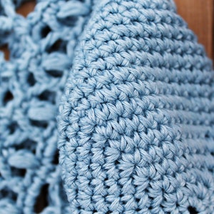 May include: Close-up of a light blue crocheted fabric with a textured, woven pattern.
