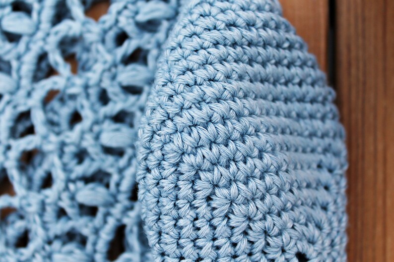 May include: Close-up of a light blue crocheted fabric with a textured, woven pattern.