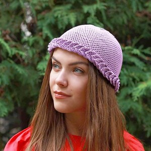 A purple crocheted hat with a scalloped edge. The hat is worn by a person with long brown hair. Breathable mesh design for summer.