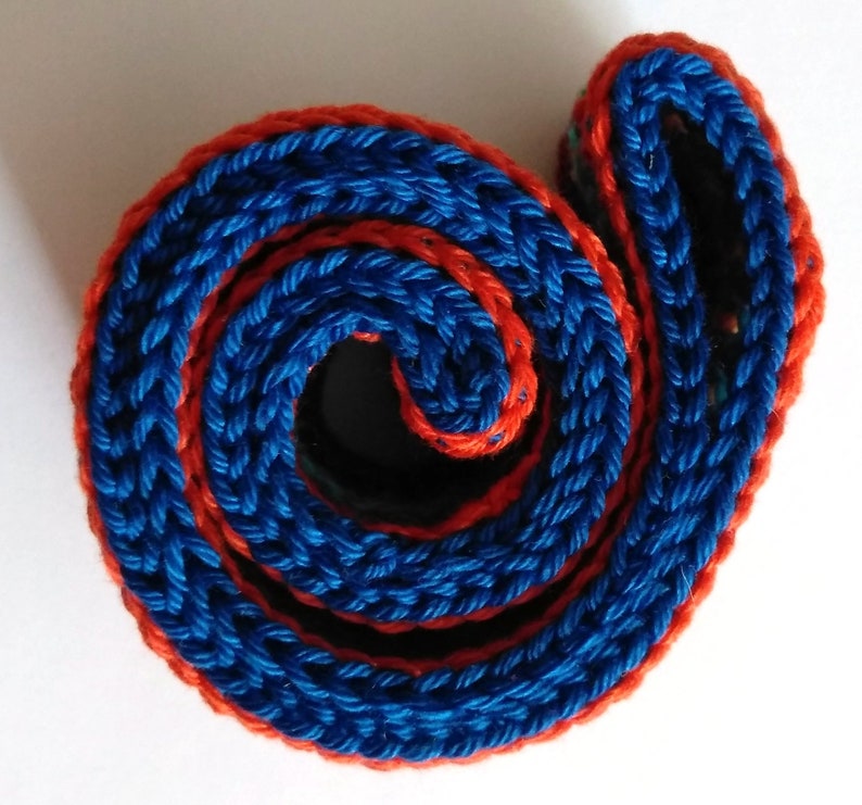 K&ouml;nnte beinhalten: Nahaufnahme eines aufgerollten geflochtenen Seils in Blau und Orange. Das Seil ist mit einem dicken, strukturierten Muster gewebt.