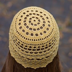 Close-up photo from the back of the head showing the crocheted pattern of the woman's summer hat.