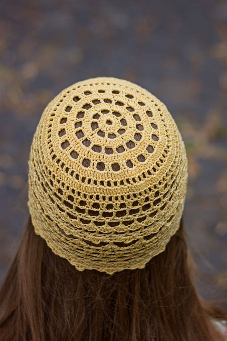 Close-up photo from the back of the head showing the crocheted pattern of the woman's summer hat.