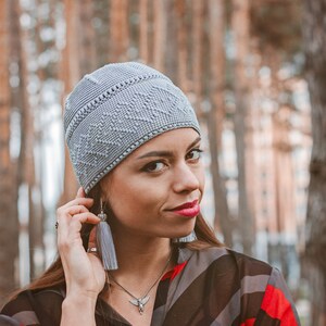 A woman in a snug-fitting gray beanie hat crocheted with a simple dense stitch.