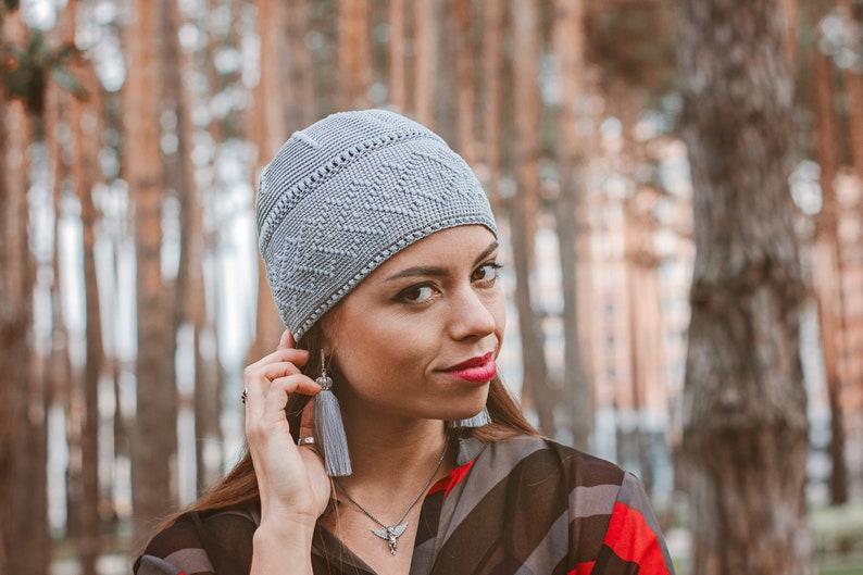 A woman in a snug-fitting gray beanie hat crocheted with a simple dense stitch.