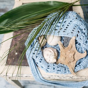 Delicate half-moon shaped crochet bag, shown in soft blue with beach-inspired styling – perfect for sunny days