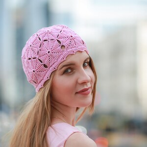 A lovely woman with long light hair showcases a crocheted beret featuring pentagon motifs during a city stroll