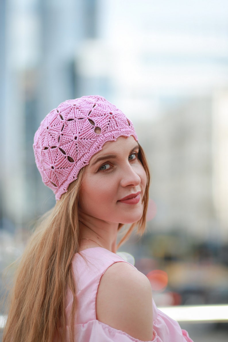 A lovely woman with long light hair showcases a crocheted beret featuring pentagon motifs during a city stroll