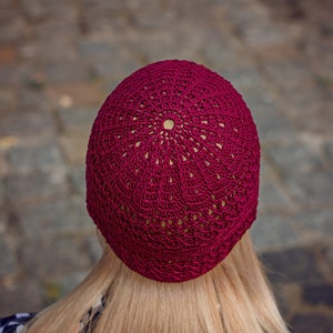 May include: A burgundy crocheted beanie with a circular pattern.
