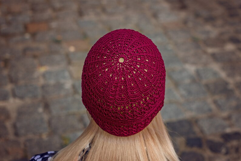 May include: A burgundy crocheted beanie with a circular pattern.