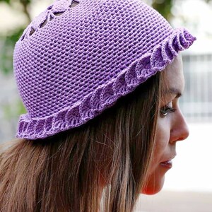 A purple crocheted hat with a scalloped brim and a delicate openwork design on the crown. Made of fingering weight cotton yarn.
