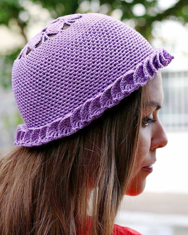 A purple crocheted hat with a scalloped brim and a delicate openwork design on the crown. Made of fingering weight cotton yarn.