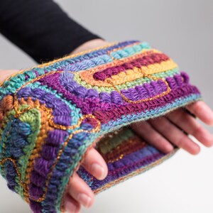 May include: A colorful crocheted headband with a multi-colored striped pattern and gold accents.