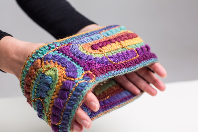 May include: A colorful crocheted headband with a multi-colored striped pattern and gold accents.