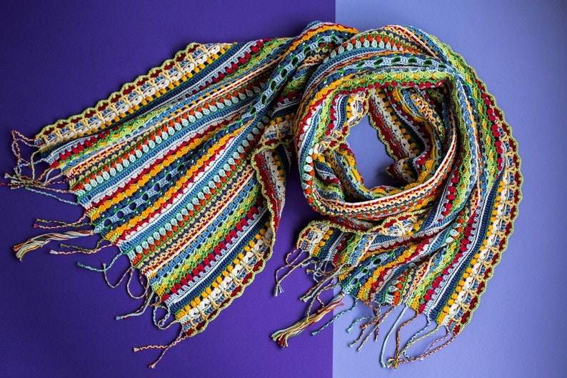 The twisted multicolor crohet scarf lies on a purple background.