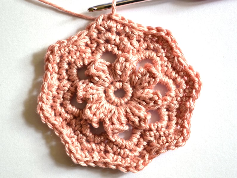 May include: A pink crocheted flower motif with a six-pointed star shape.