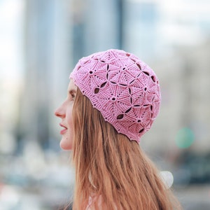 A profile of a woman against the city backdrop, showcasing a handmade crocheted beret.