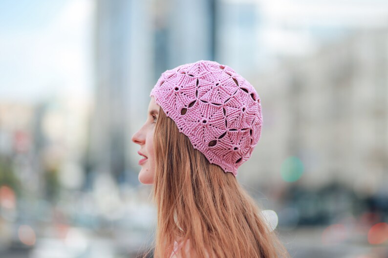 A profile of a woman against the city backdrop, showcasing a handmade crocheted beret.