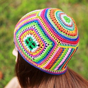 May include: A colorful crocheted hat with a geometric pattern in shades of pink, orange, yellow, green, blue, and white.