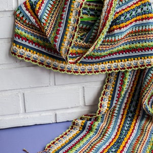 A multi-colored crocheted scarf is draped over the shoulders as an accessory.