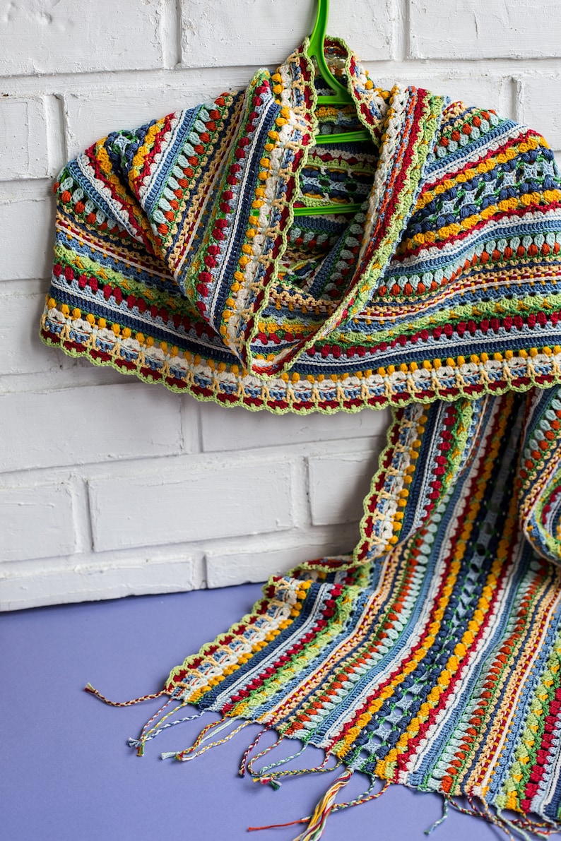 A multi-colored crocheted scarf is draped over the shoulders as an accessory.