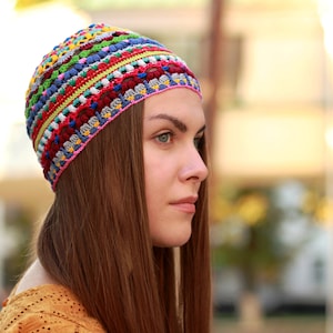 The hat features a regular crochet design. It's bright and multicolored, worn on a woman's head.