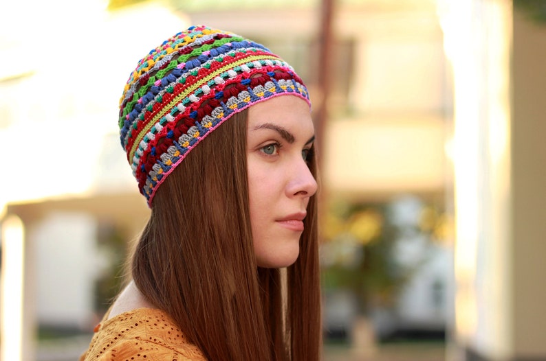 The hat features a regular crochet design. It's bright and multicolored, worn on a woman's head.