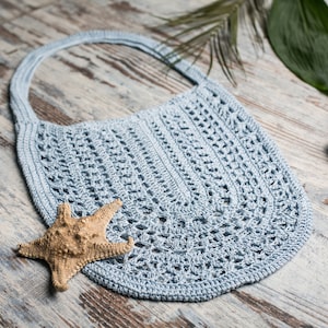 May include: A light blue crocheted tote bag with a starfish on a wooden surface.