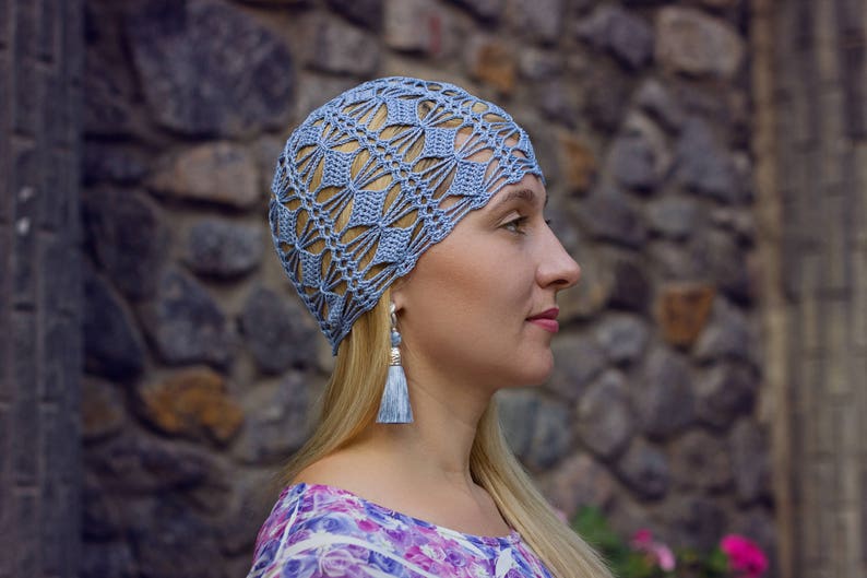 A crochet blue hat is showcased on the side profile of a woman's head.