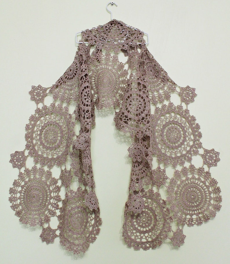 Beige lace crochet scarf hanging full length on a hanger against a light background, designed by Ukrainian designer Kate Kosenko Veselunka (ItWasYarn).