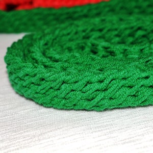 May include: A close-up of a green braided rope coiled into a circle. The rope is made of a soft, textured material.