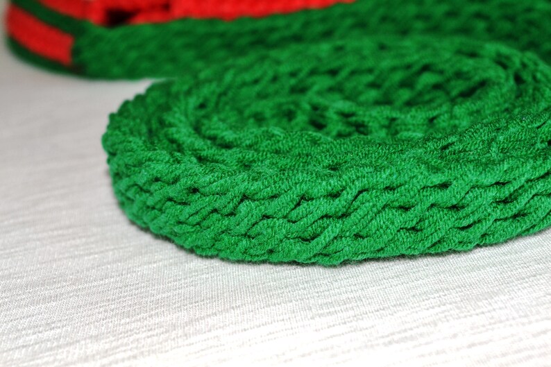 May include: A close-up of a green braided rope coiled into a circle. The rope is made of a soft, textured material.